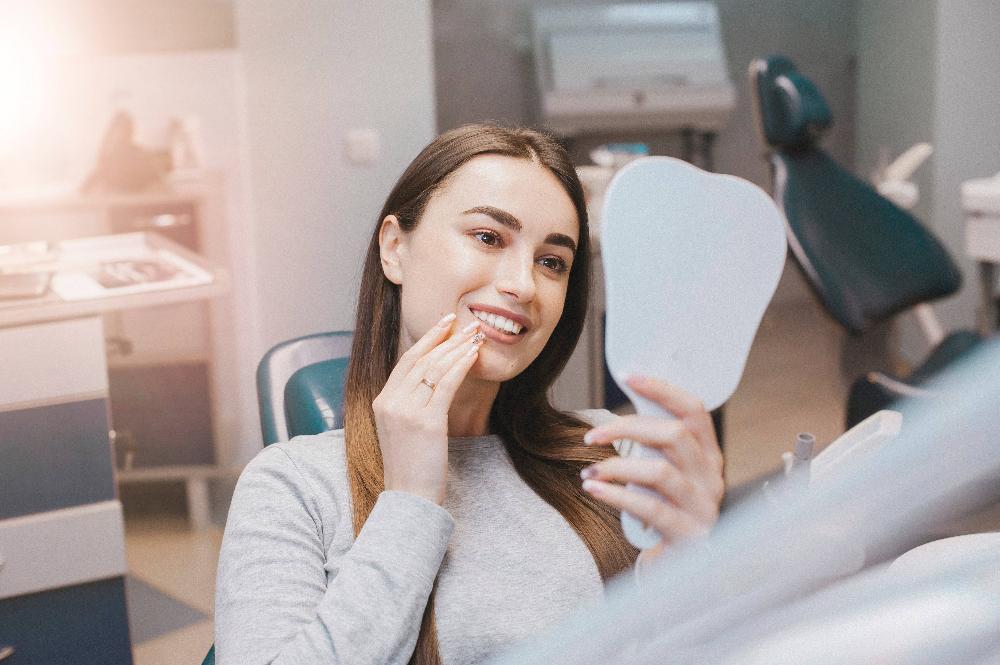 woman sitting in dental exam chair with mirror l dentist austin