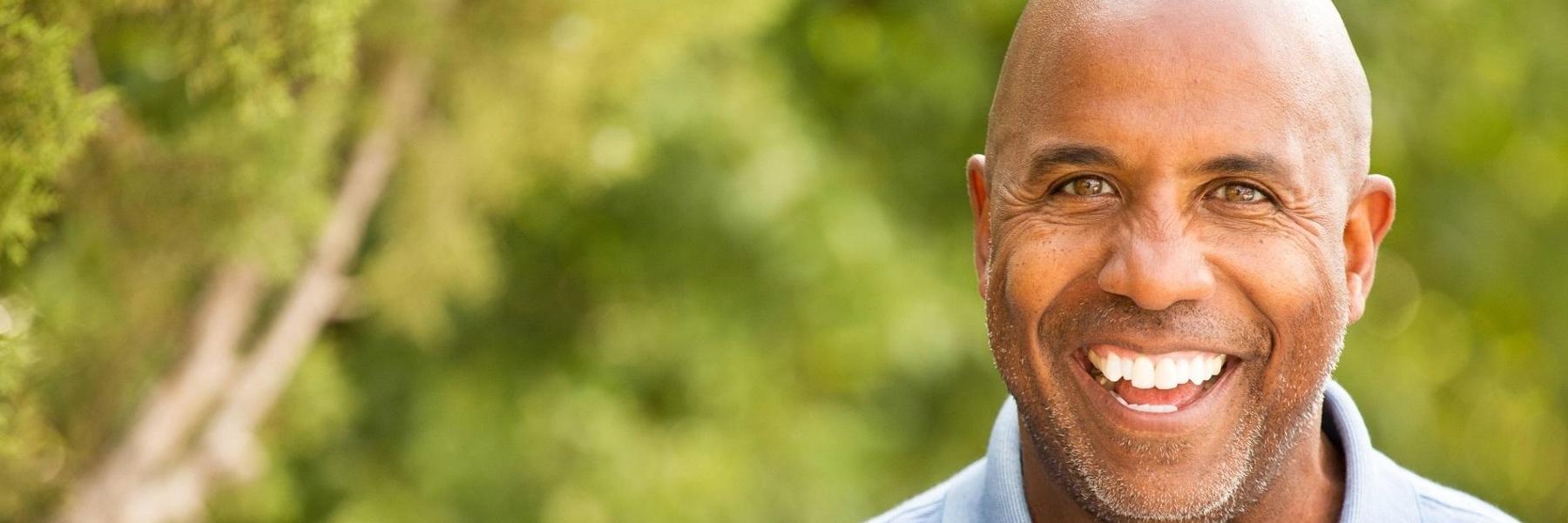 man with bright smile outside l dental crowns austin tx