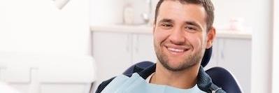 man sitting in dental exam chair smiling l dental clinic austin tx