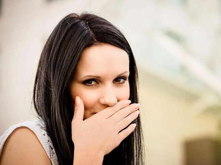 Younger woman with brown hair covering her smile, austin tx