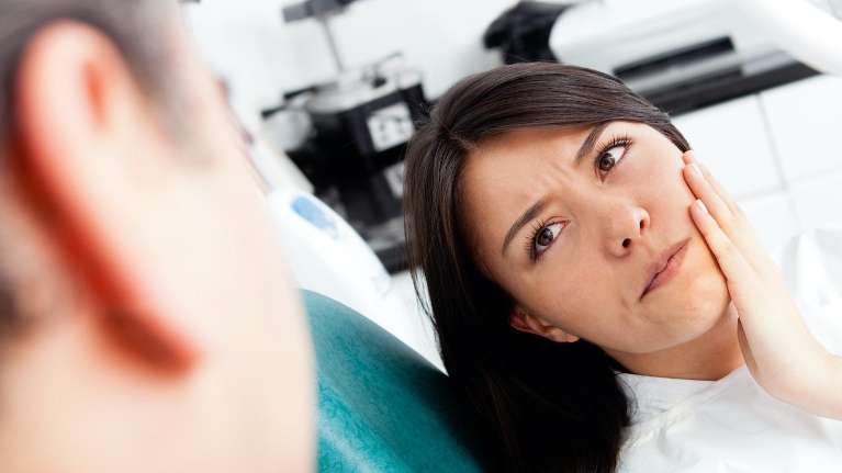 woman holding her jaw from an infected tooth